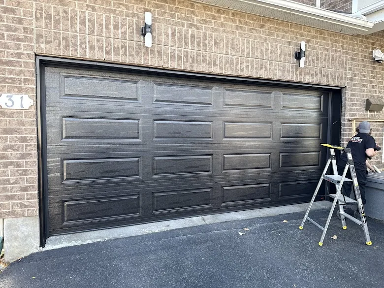 Affordable Door Co technician installing black garage door on brick home in OKC